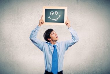 Jeune homme montrant un dessin de visage souriant sur une ardoise