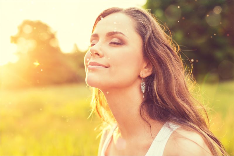 Femme avec les yeux fermés dans un près en été, heureuse