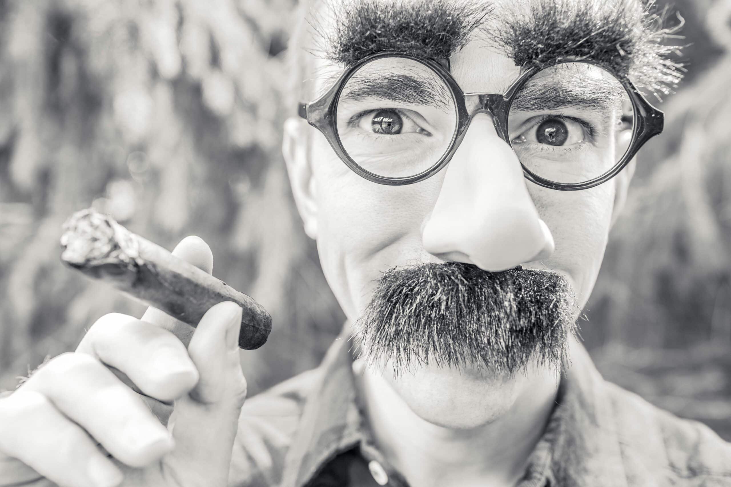 Homme portant un déguisement de fausses lunettes, nez et moustache, symbole visuel du masque et de la fausse identité associés au syndrome de l'imposteur au travail